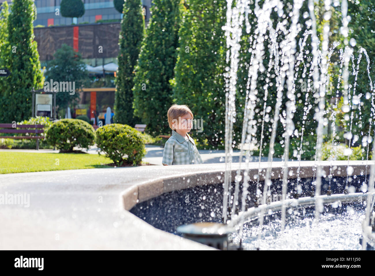 Three years old child in the park with water fountain and blue sky Stock Photo