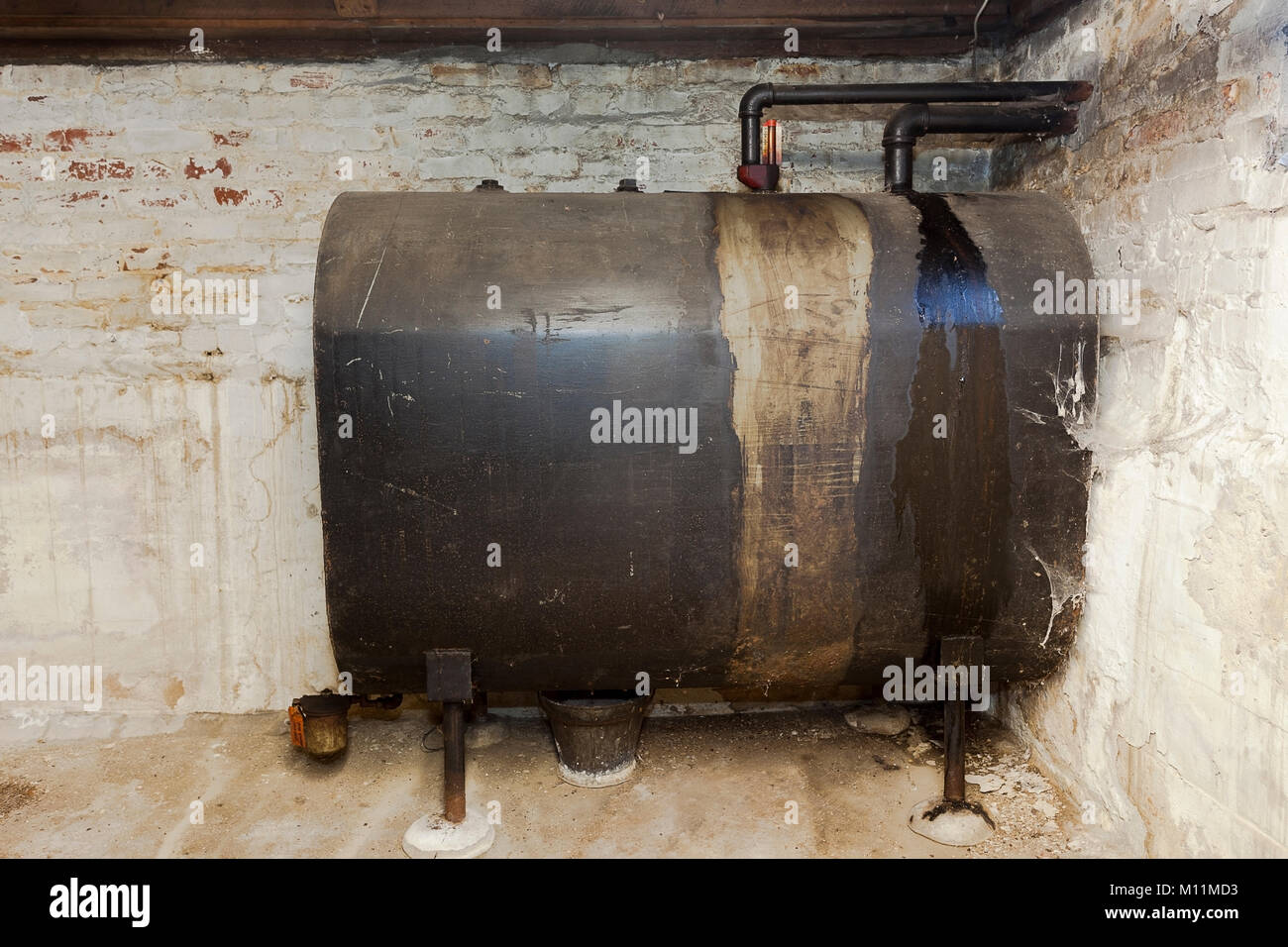 Old heating oil tank in dingy dank basement. Stock Photo