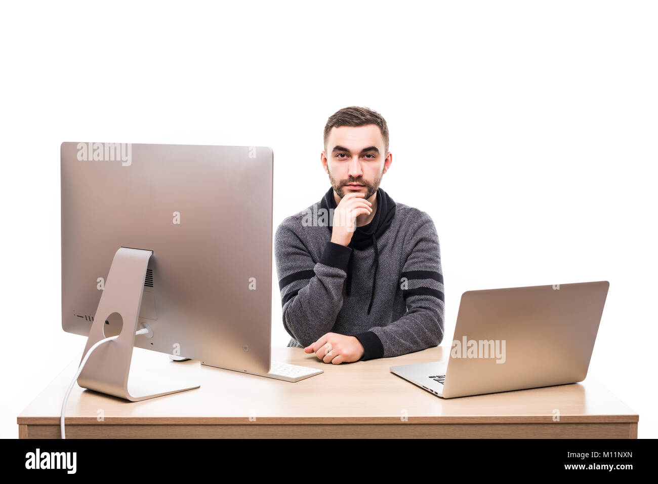 smiley successful businessman sitting at the table with laptop and personal computer and looking at camera isolated on white background Stock Photo