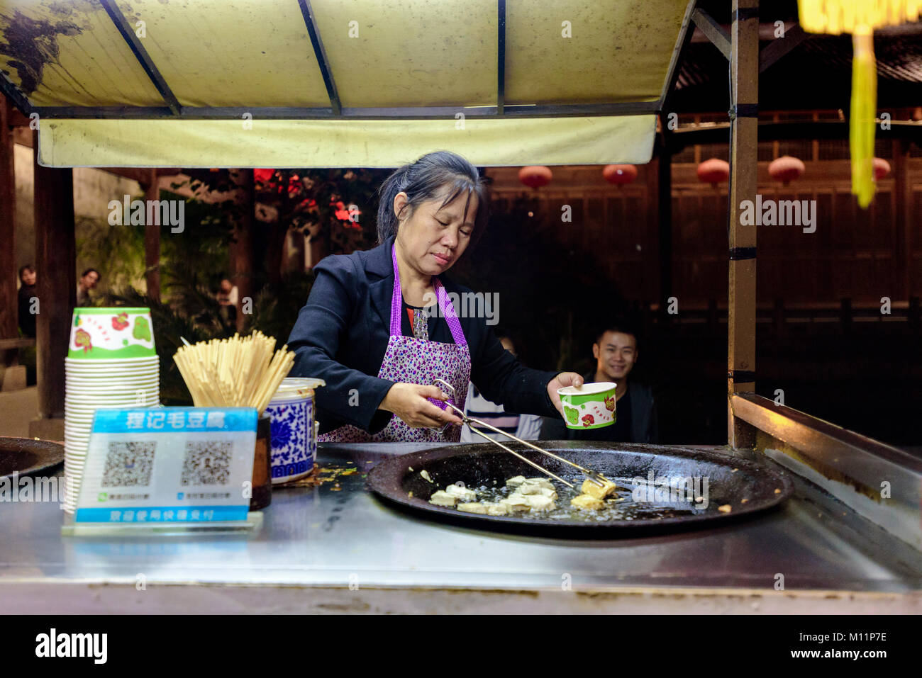 Huangshan City, China. A local woman cooks the regional specialty hairy tofu on the Tunxi Ancient Street, or 'Old Street.' Credit: Benjamin Ginsberg Stock Photo