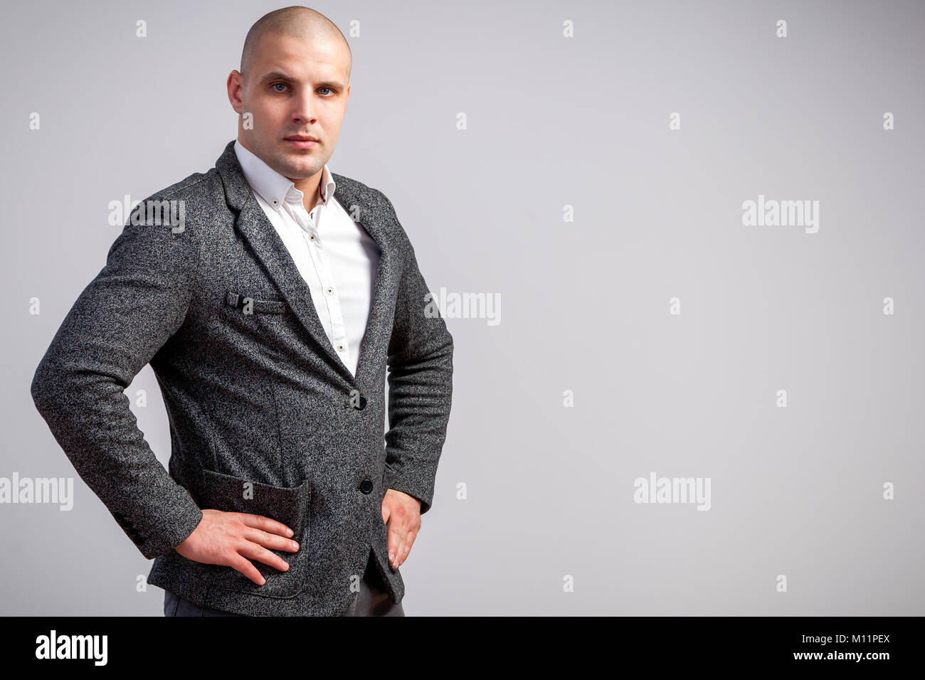 Young bald man in white shirt, gray suit confidently looks at camera and posing on white isolated background Stock Photo