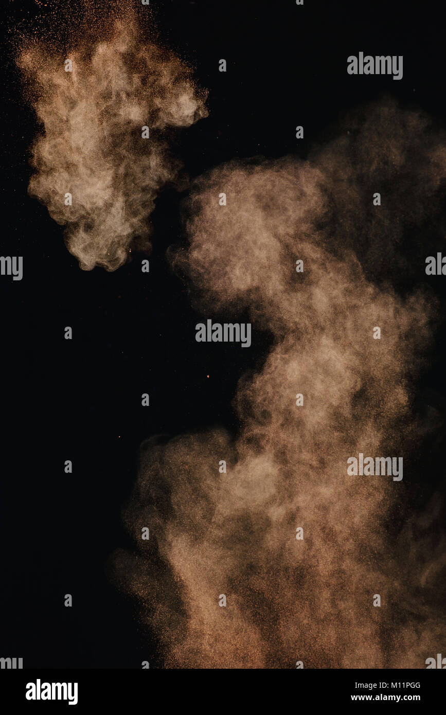 Cocoa powder explosion in motion. Chocolate dust on a black background. Action food photography