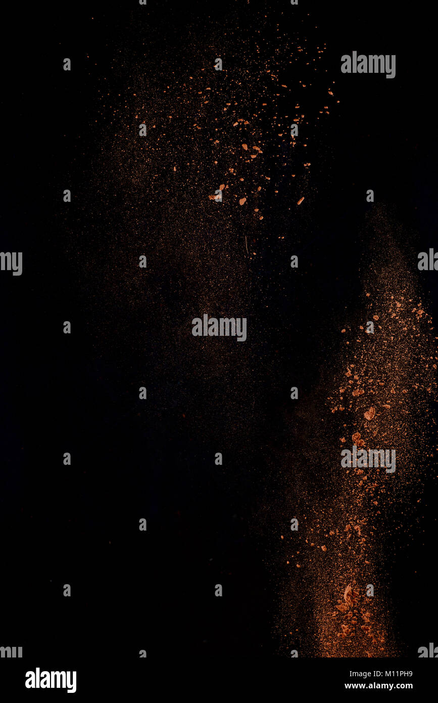 Cocoa powder explosion in motion. Chocolate dust on a black background. Action food photography