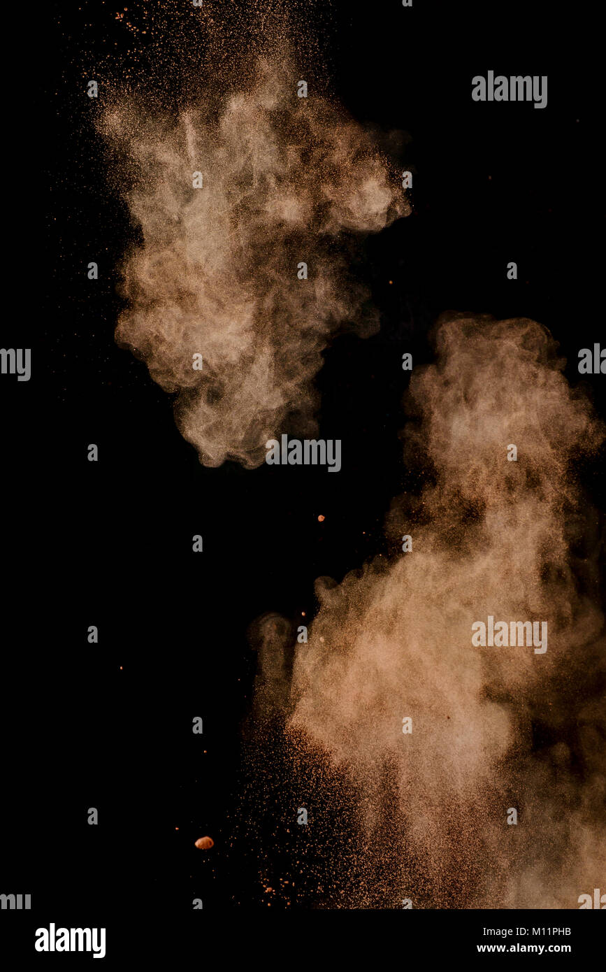 Cocoa powder explosion in motion. Chocolate dust on a black background. Action food photography