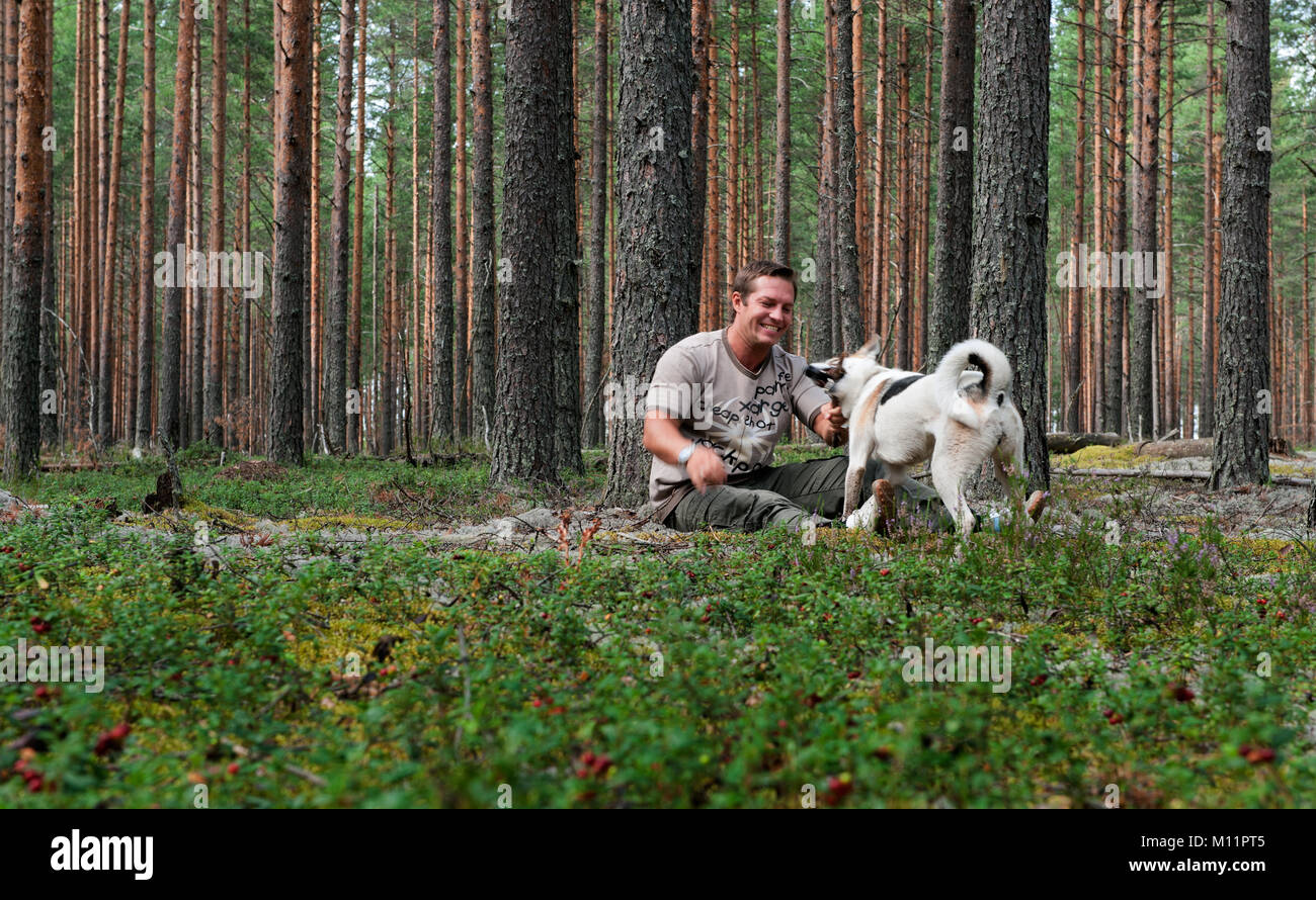 The man is resting in the forest and playing with dog Stock Photo - Alamy