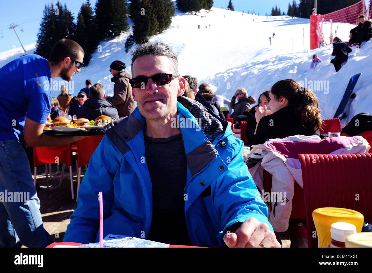 Eating in an outside ski resort restaurant on a sunny day, Samoens France Stock Photo
