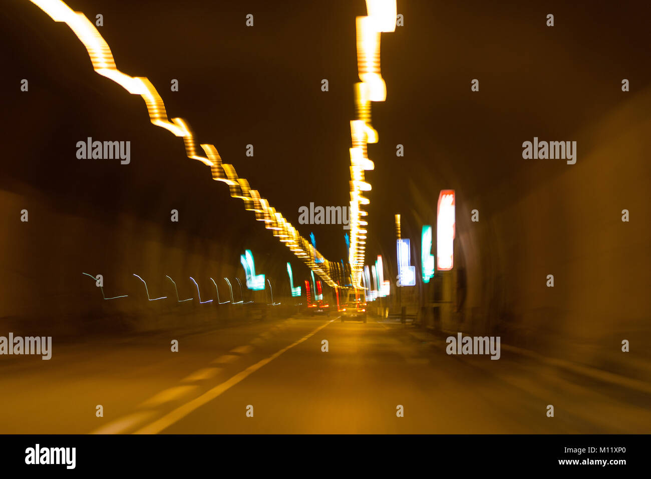 cars in motorway tunnel at night with blurred trail lights Stock Photo