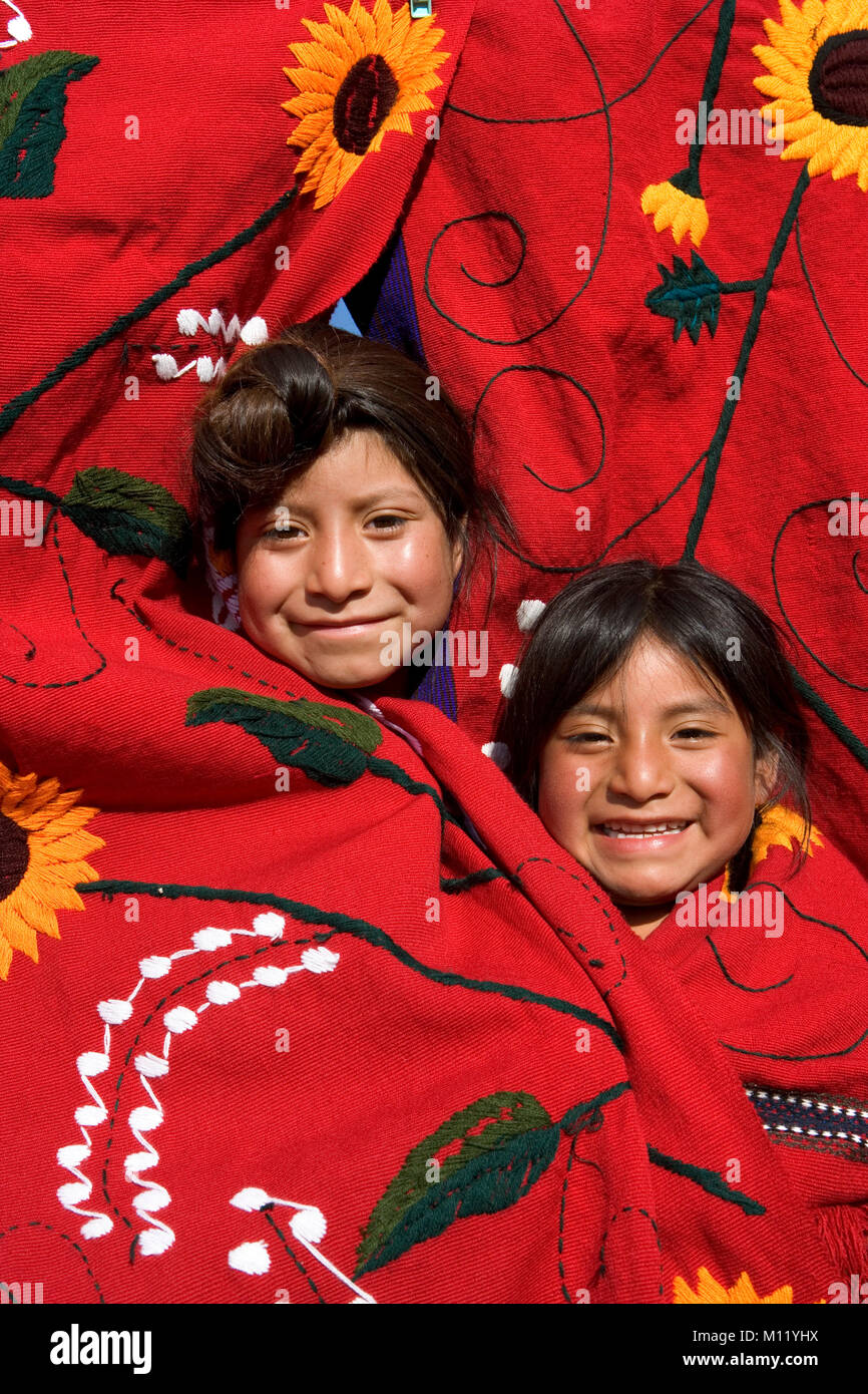 Mexico. Chiapas. Amatenango del Valle. Ethnic group of Tzeltal Indians. Two girls poking heads out from hanging cloth, smiling, portrait. Stock Photo