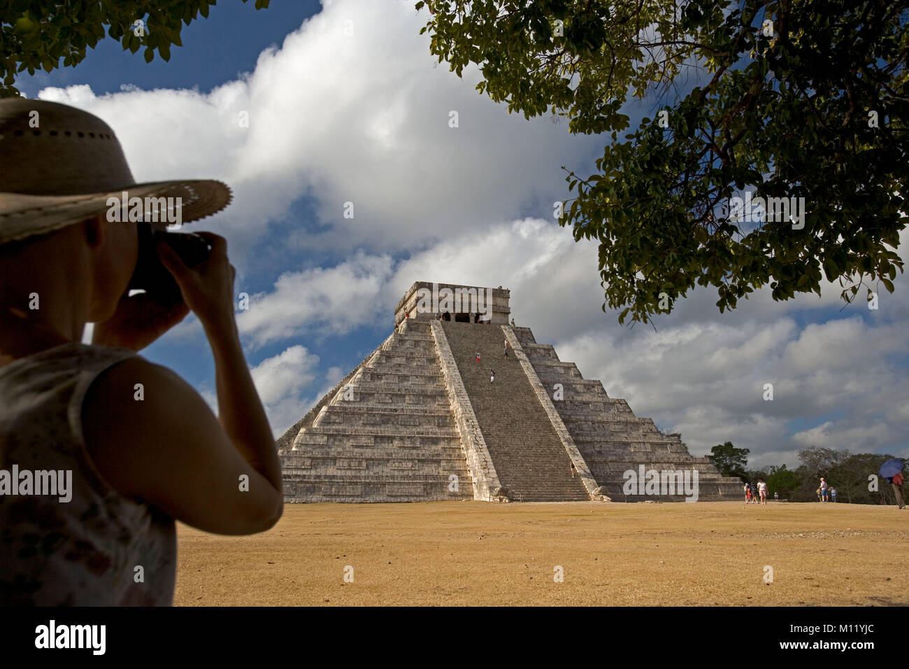 Mexico. Yucatan. Chichen Itza. Maya ruins. Maya-Toltec ruins, El Castillo. Female tourist taking photo of pyramid. Stock Photo