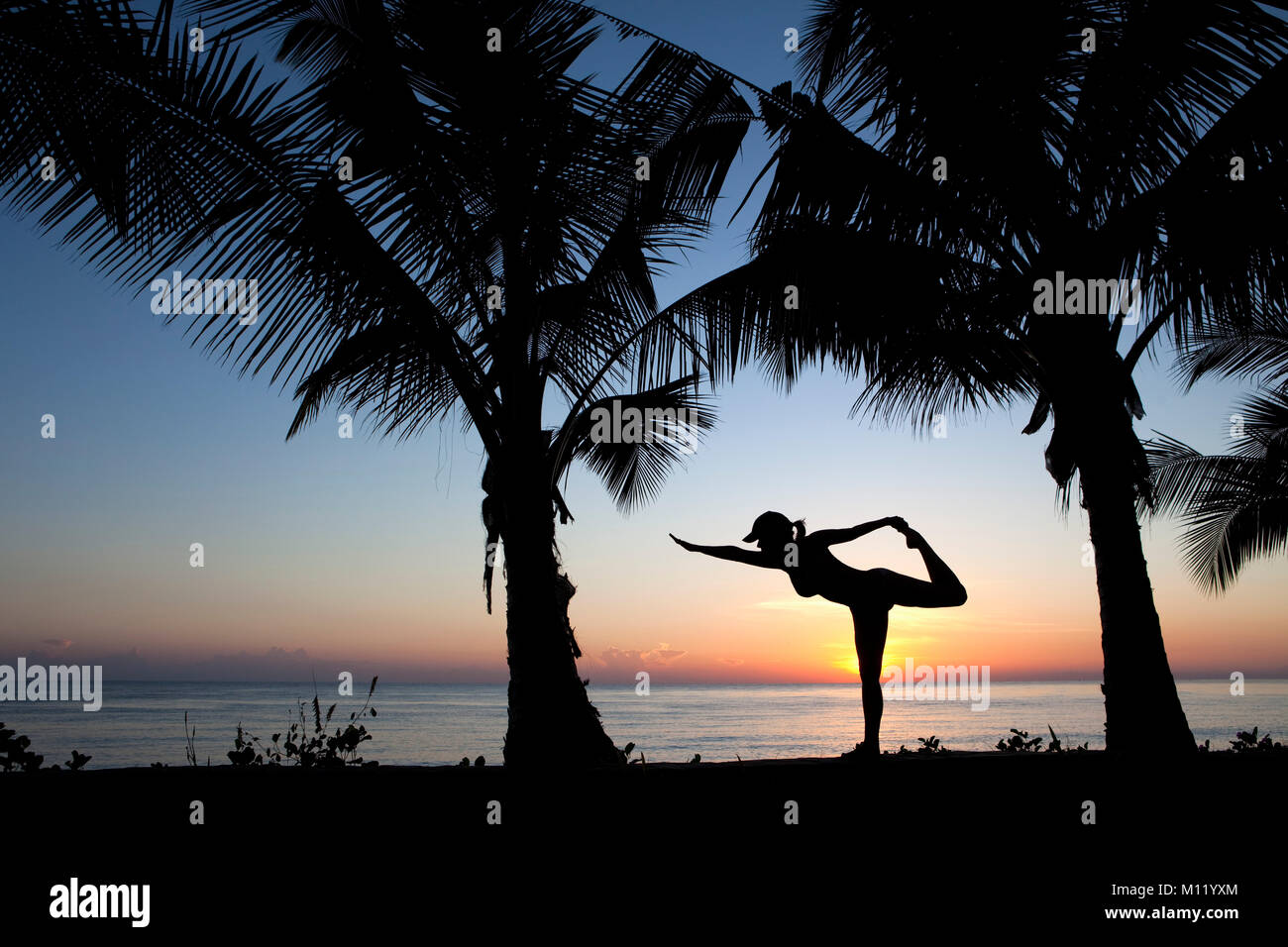 Indonesia, Island Bali, near Tejakula village, Gaia Oasis Resort. Woman performing yoga exercise at sunrise. Stock Photo