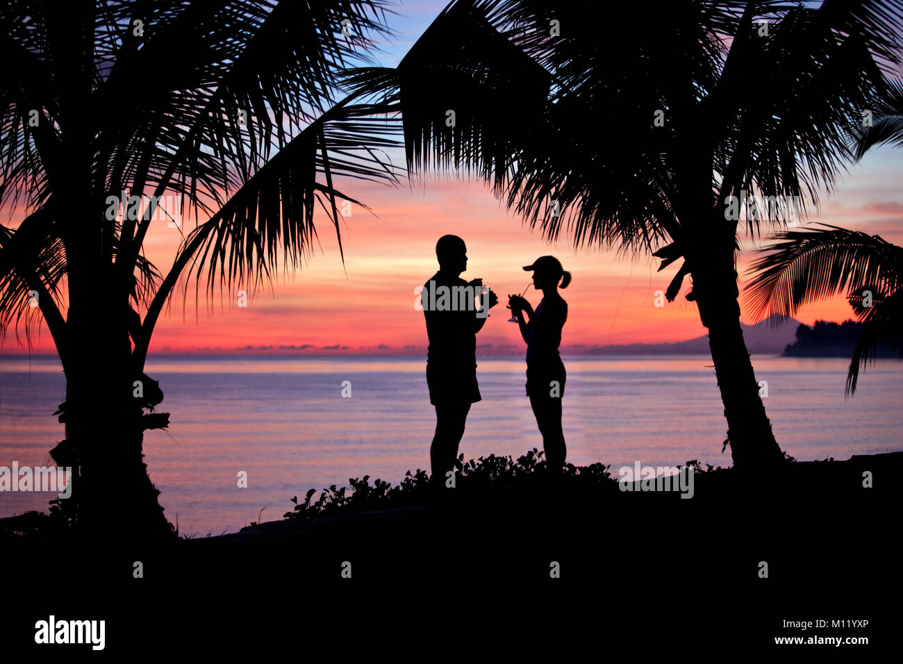 Indonesia, Island Bali, near Tejakula village, Gaia Oasis Resort. Couple having a drink at sunset. Stock Photo