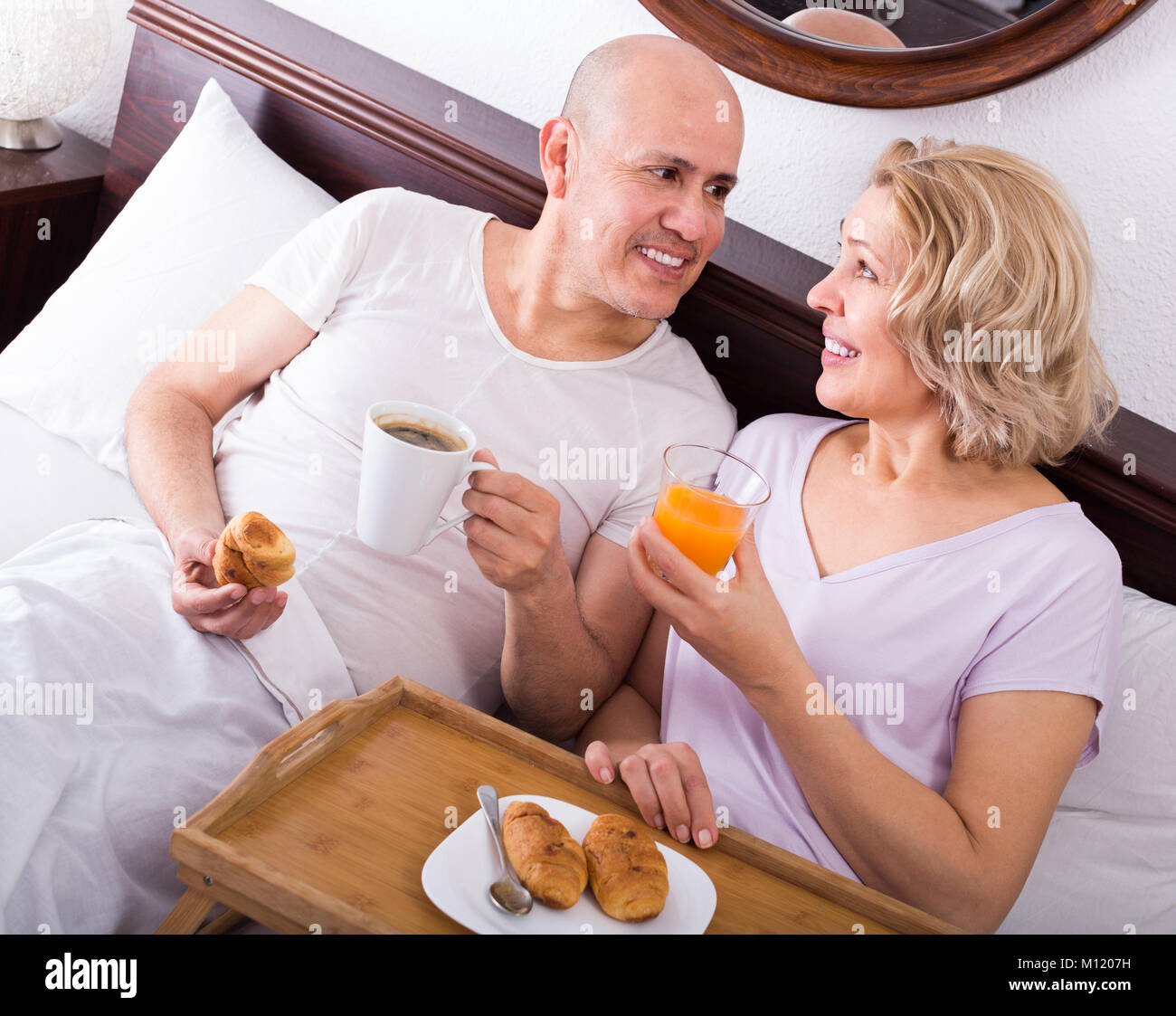 Mature adults 50-60 years old posing with coffee and pastry for breakfast Stock Photo