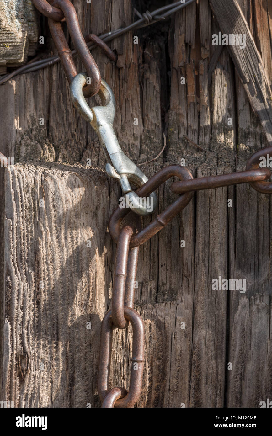 Lobster claw clasp and chain on a gate post in rural Eastern Oregon. Stock Photo