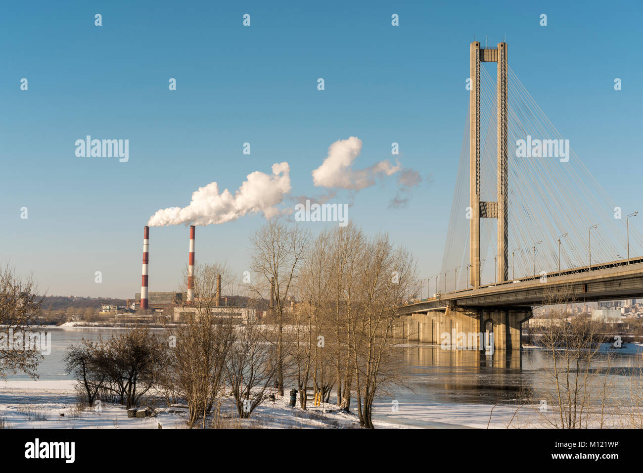 Two large smoking pipes on the river bank against the blue sky. White
