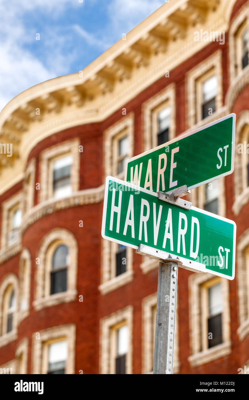 Harvard name on street sign post in Cambridge, Mass. Sign close up in the foreground. Typical red brick Ivy League building in the background. Stock Photo