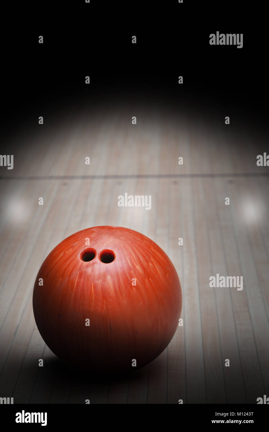 Bowling ball on hardwood bowling alley with special spot lighting effect. Focus on foreground