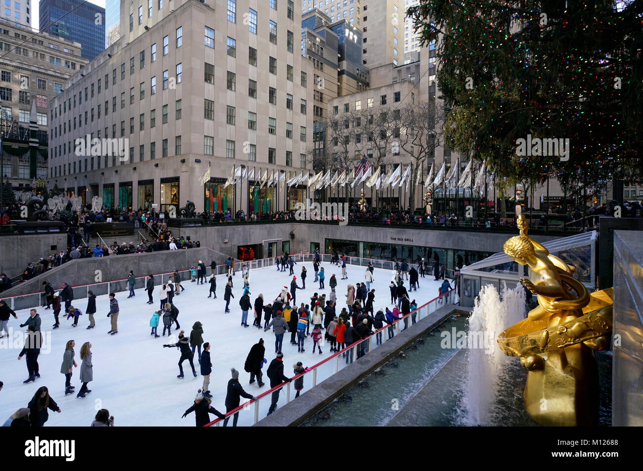 The ice skating rink in Rockefeller Center with the golden Prometheus sculpture in foreground.winter holiday season.Manhattan.New York City.USA Stock Photo