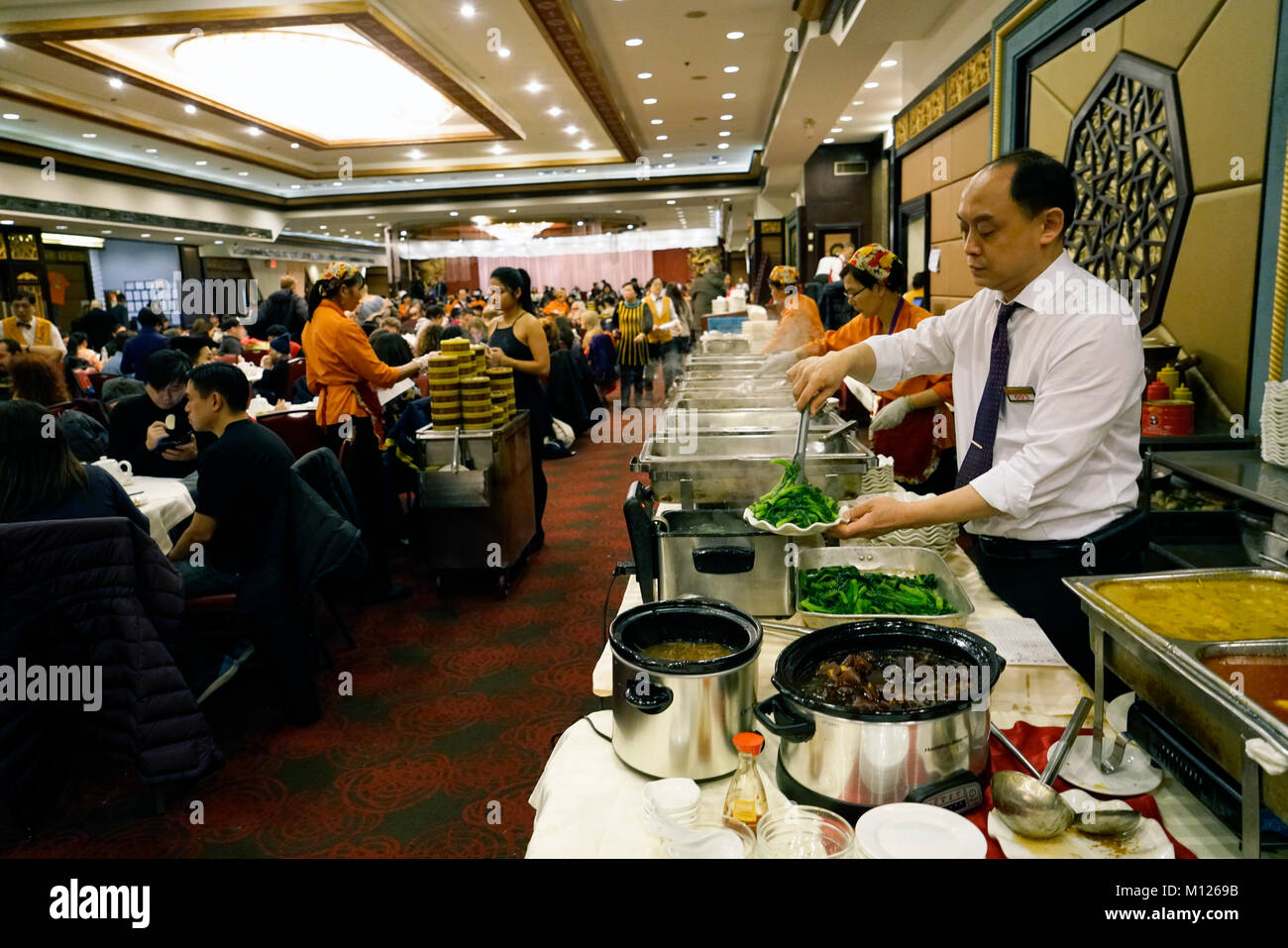 A Chinese waiter preparing food at buffet table in always crowded Jing Fong Chinese restaurant in Chinatown.Manhattan.New York City.USA Stock Photo