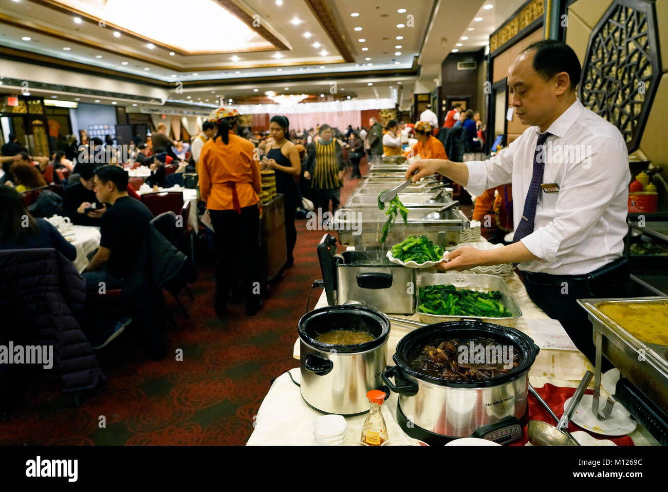 A Chinese waiter preparing food at buffet table in always crowded Jing Fong Chinese restaurant in Chinatown.Manhattan.New York City.USA Stock Photo