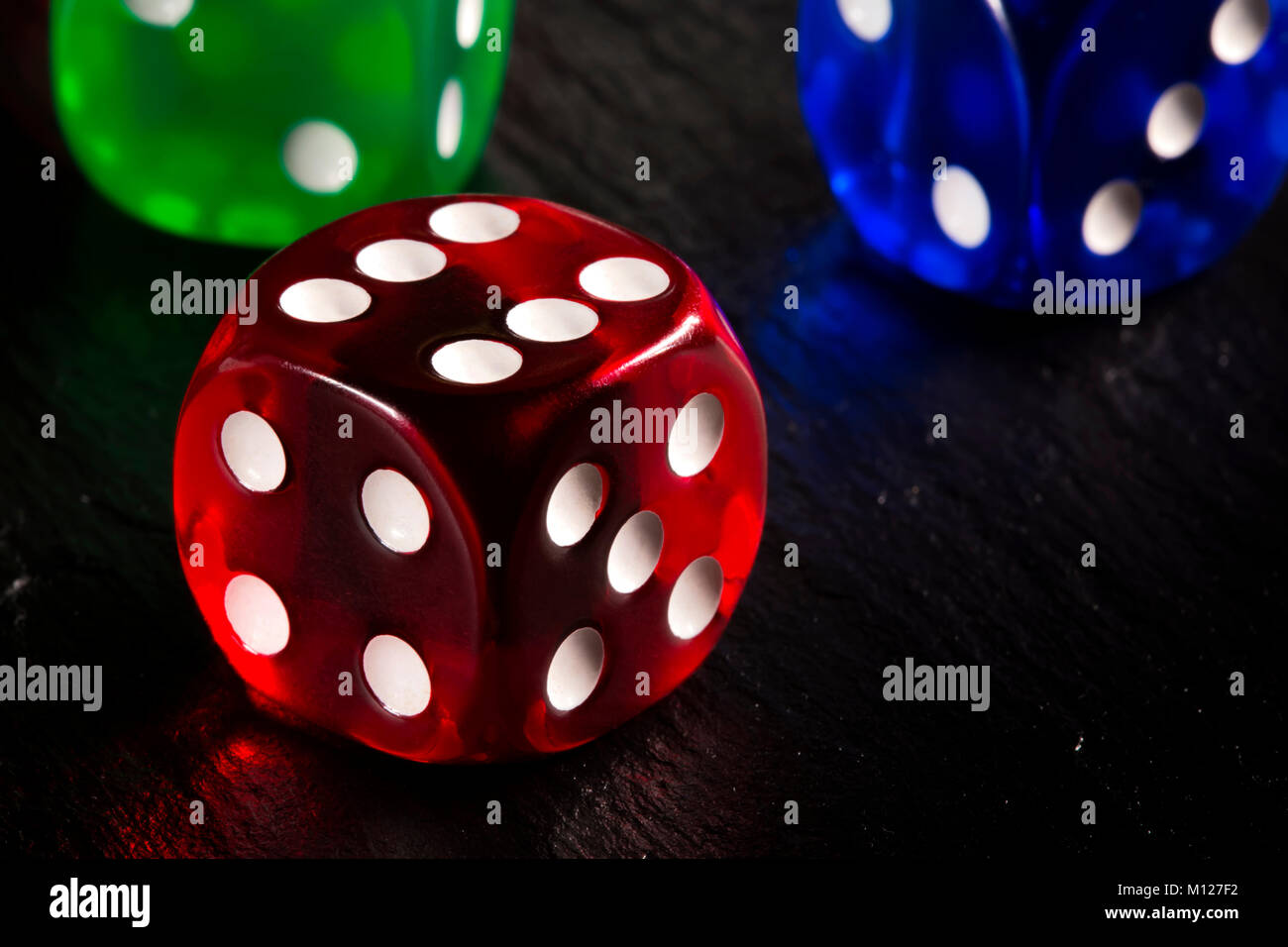 Close up of colored dices on dark slate background Stock Photo