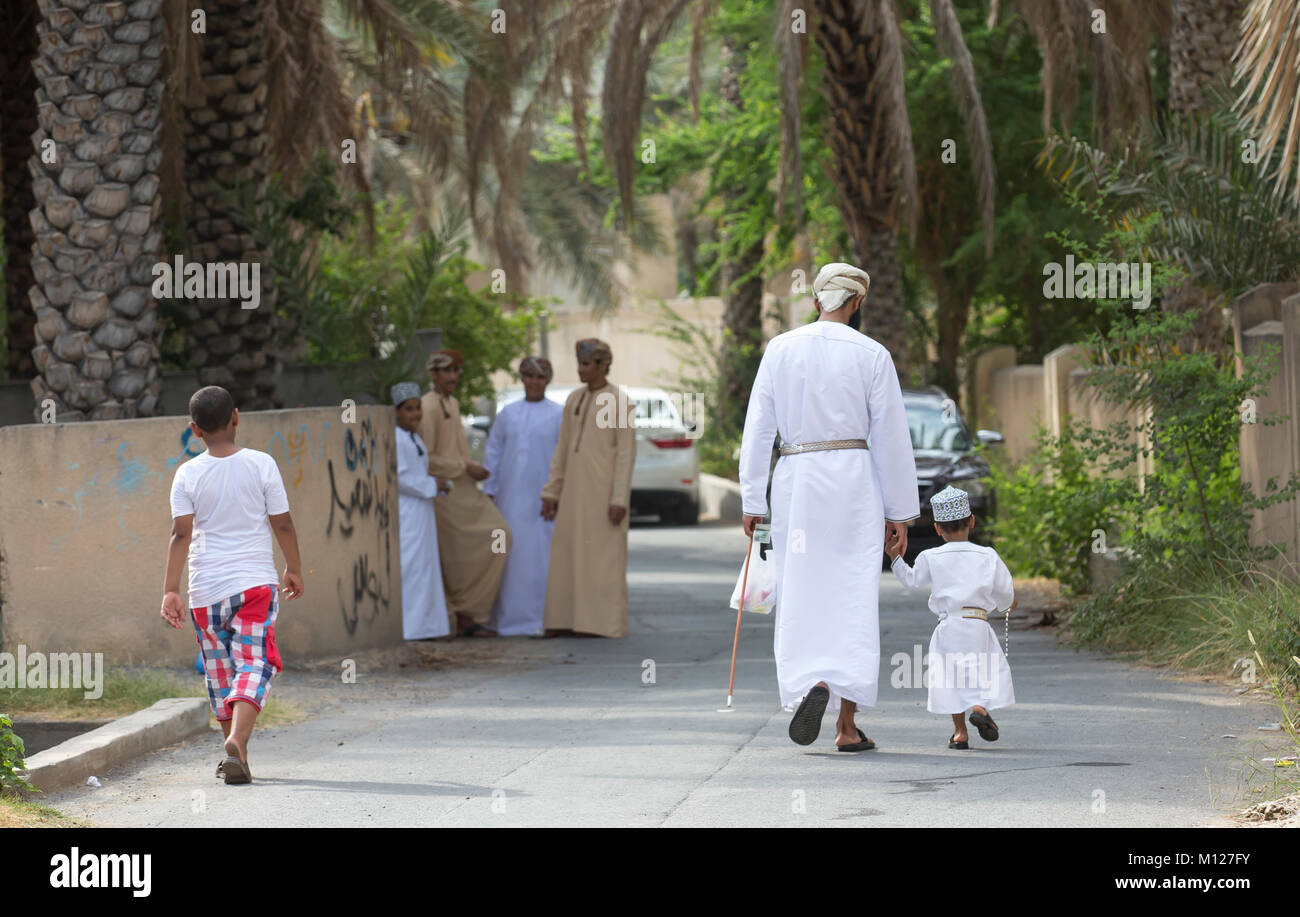 Nizwa, Oman - June 26th 2017: family in traditional clothing at a toy market on a day of Eid al Fitr, celebration at the end of Holy Month of Ramadan Stock Photo