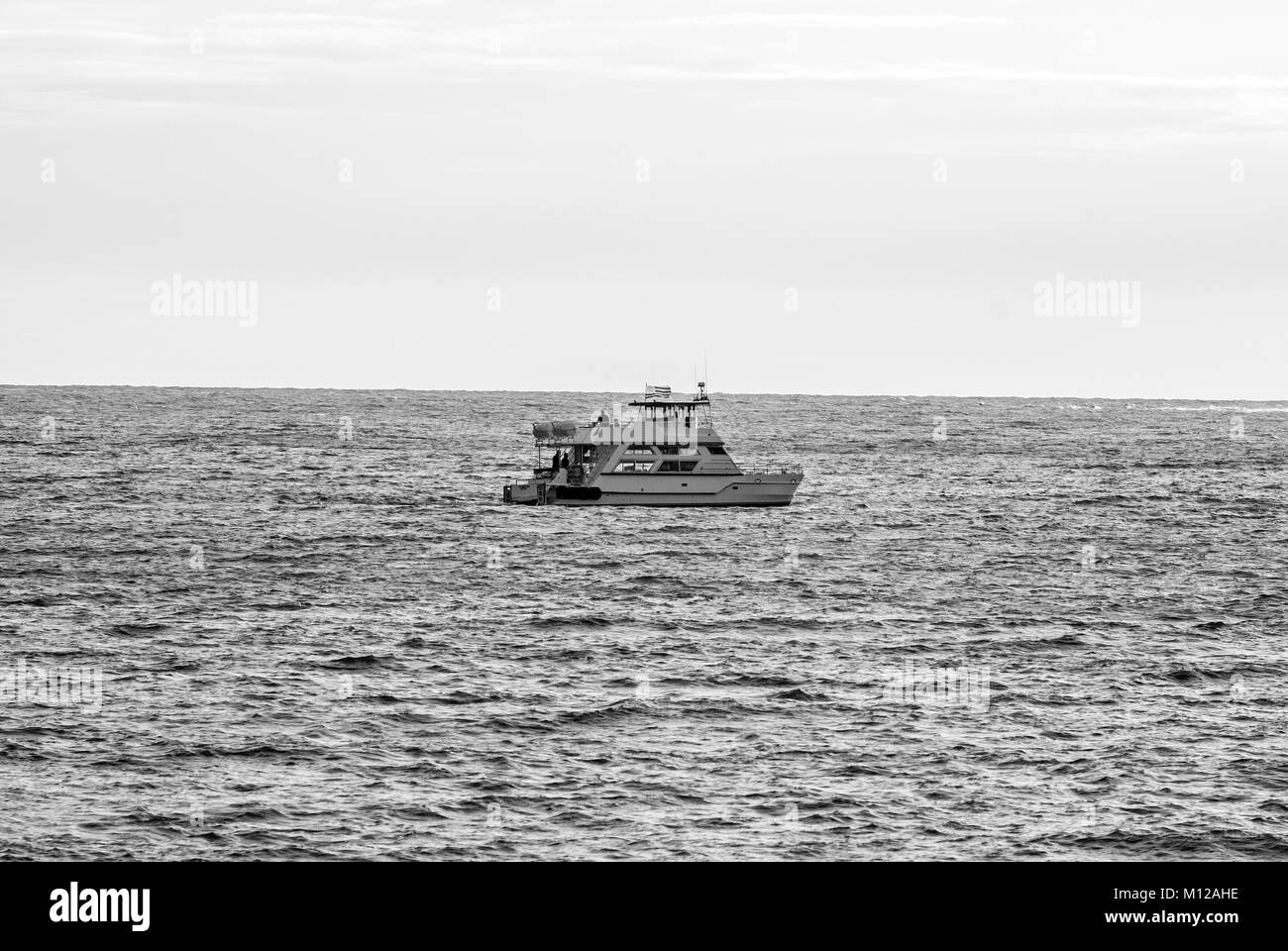 Lonely boat in the middle of the ocean. Black and white photo. Punta del Este, Uruguay Stock Photo