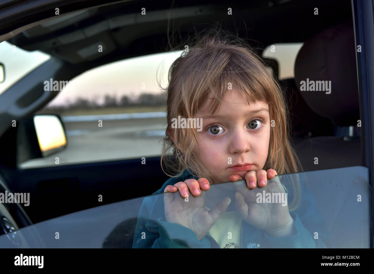 Little girl with big eyes sitting in car Stock Photo