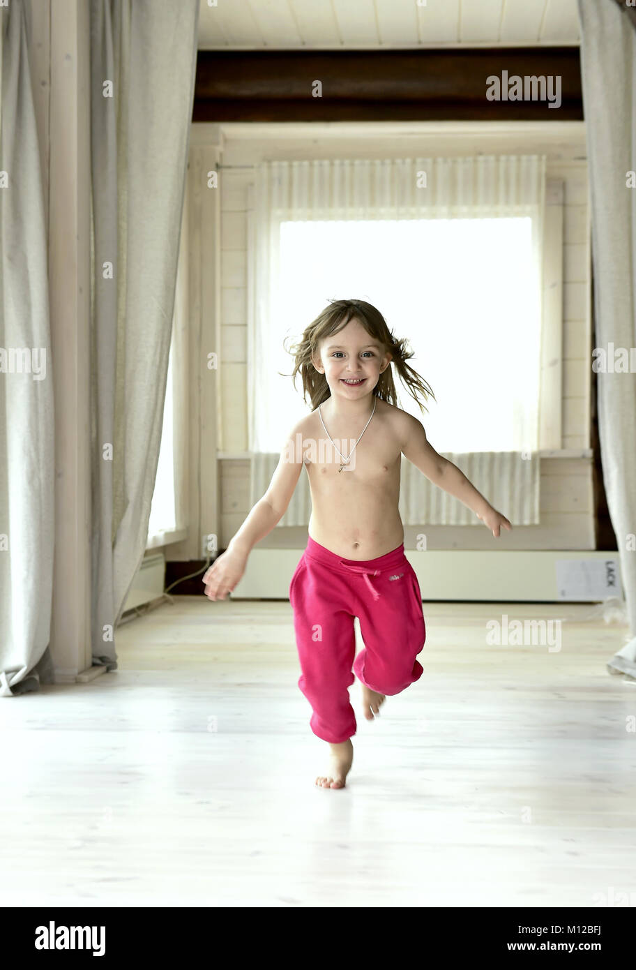 Happy smiling little girl wearing red pants on white floor Stock