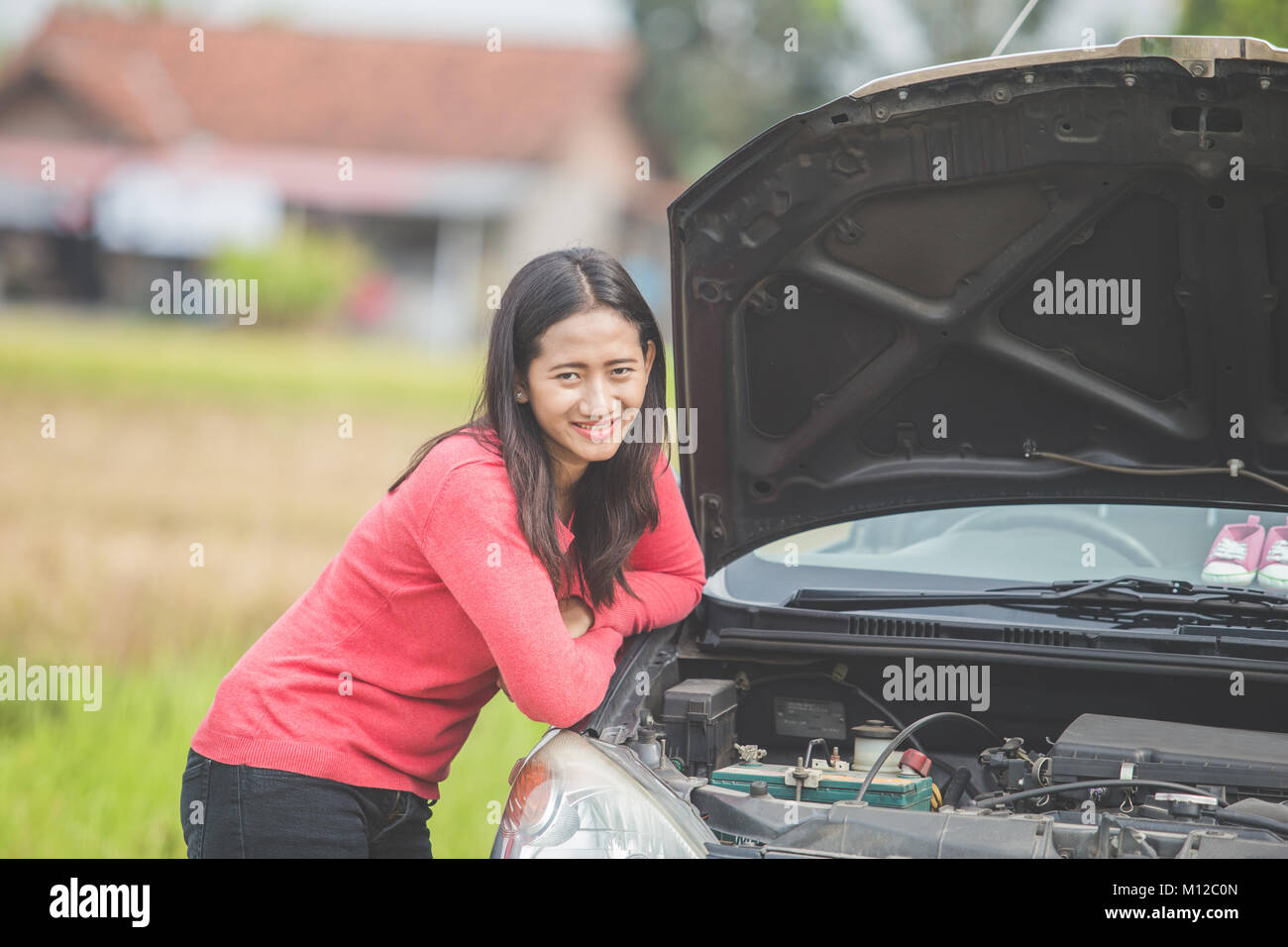 portrait of young woman standing next to her car trying to fix the ...
