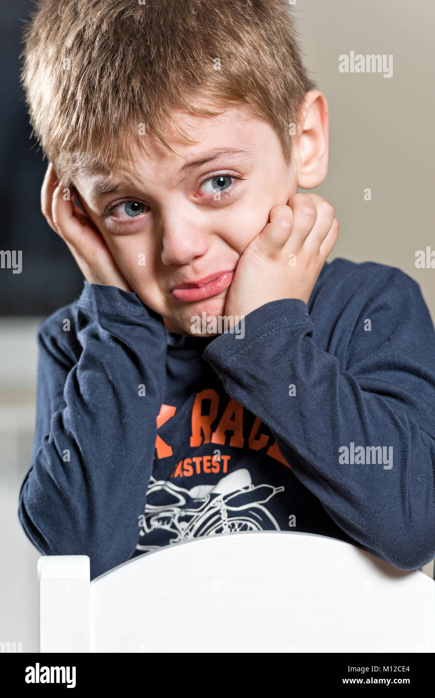 Sad little boy crying loudly, portrait, with his hands on the face, stressed out and crying with big tears Stock Photo