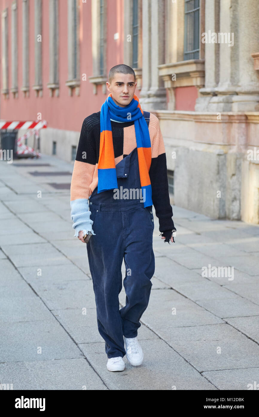 MILAN - JANUARY 14: Man with blue and orange striped scarf and blue overalls before MSGM fashion show, Milan Fashion Week street style on January 14,  Stock Photo