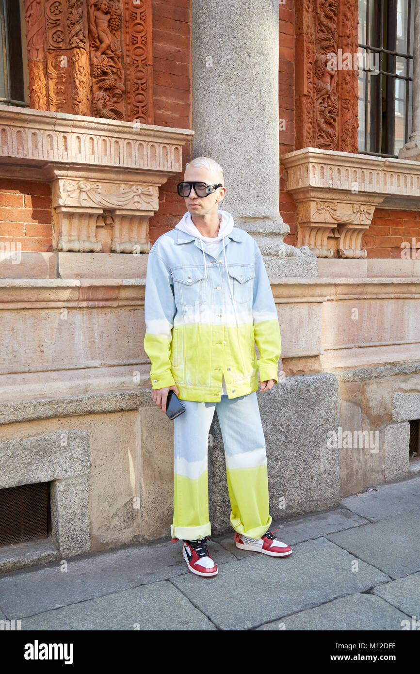 MILAN - JANUARY 14: Man with Gucci sunglasses and blue, yellow and white jeans jacket and trousers before MSGM fashion show, Milan Fashion Week street Stock Photo