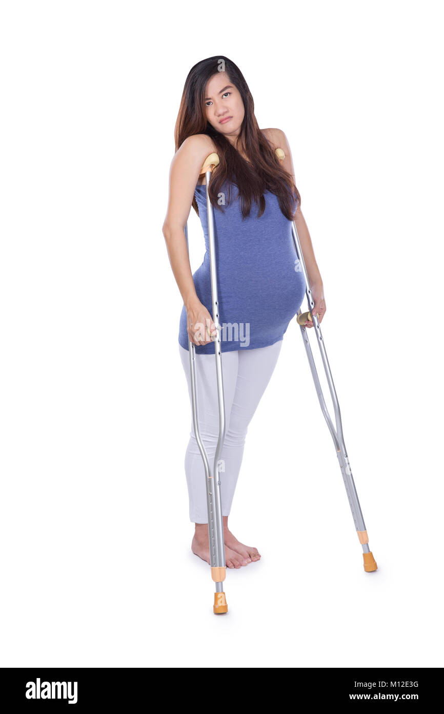 A full length portrait of a pregnant woman using crutch, isolated Stock