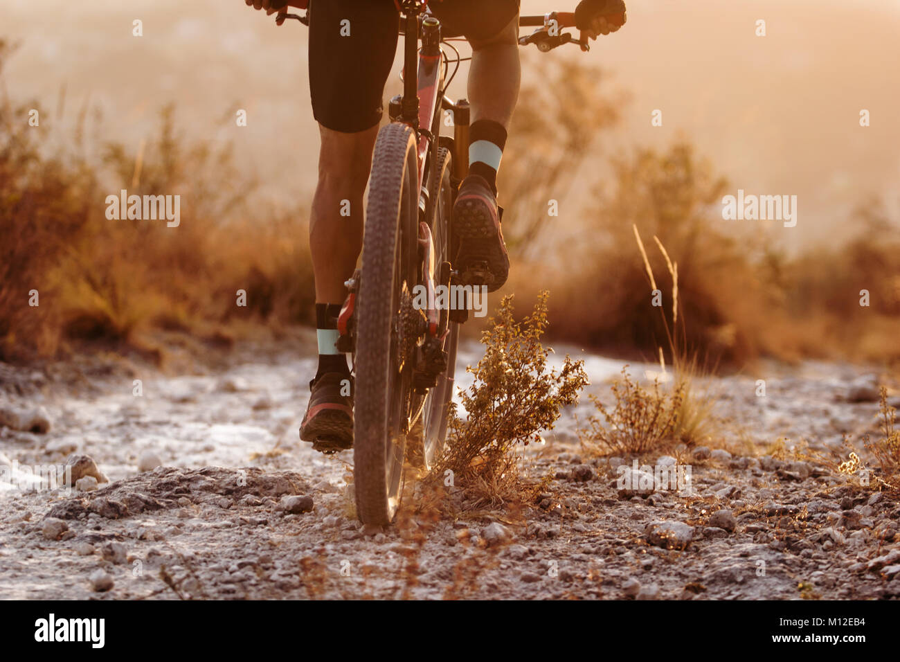 Male cyclist riding his full suspension mountain bike on dusty trail Stock Photo
