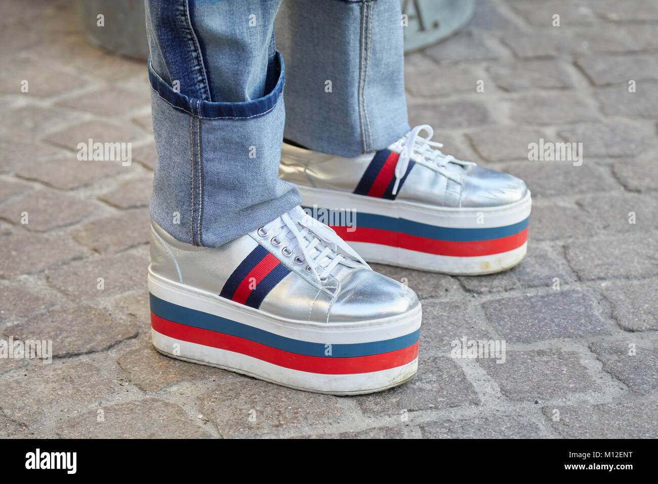 MILAN - JANUARY 14: Man with wedge heel silver sneakers in red, blue and white colors before Daks fashion show, Milan Fashion Week street style on Jan Stock Photo