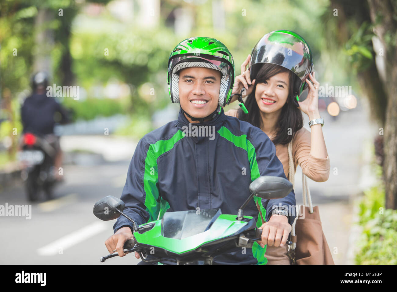 Happy commercial motorcycle taxi driver taking his passenger to her ...