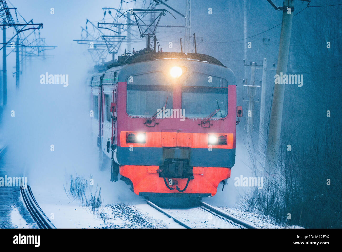 Highspeed train approaches to the station platform at snowstormy evening time. Stock Photo