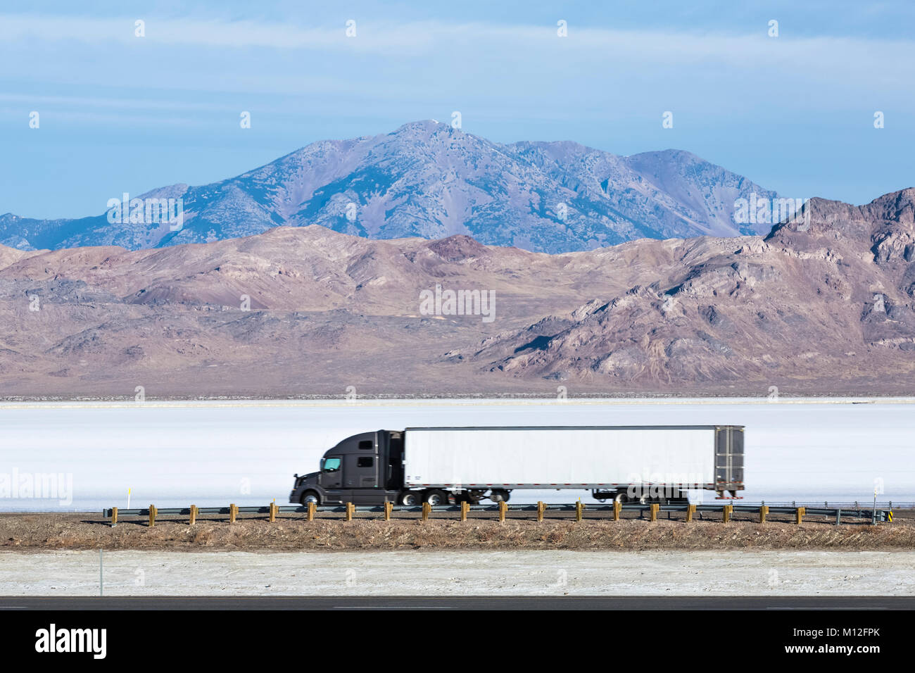 Semi truck traveling west on I-80 across the Bonneville Salt Flats, viewed from the Wendover Salt Flats Rest Area, Utah, USA Stock Photo