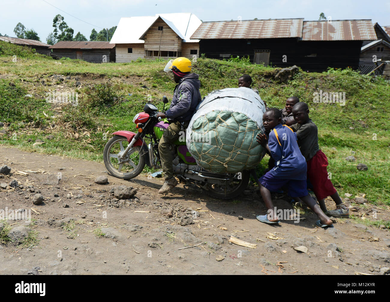 Helping a small motorbike on a bad road in eastern Congo. Stock Photo