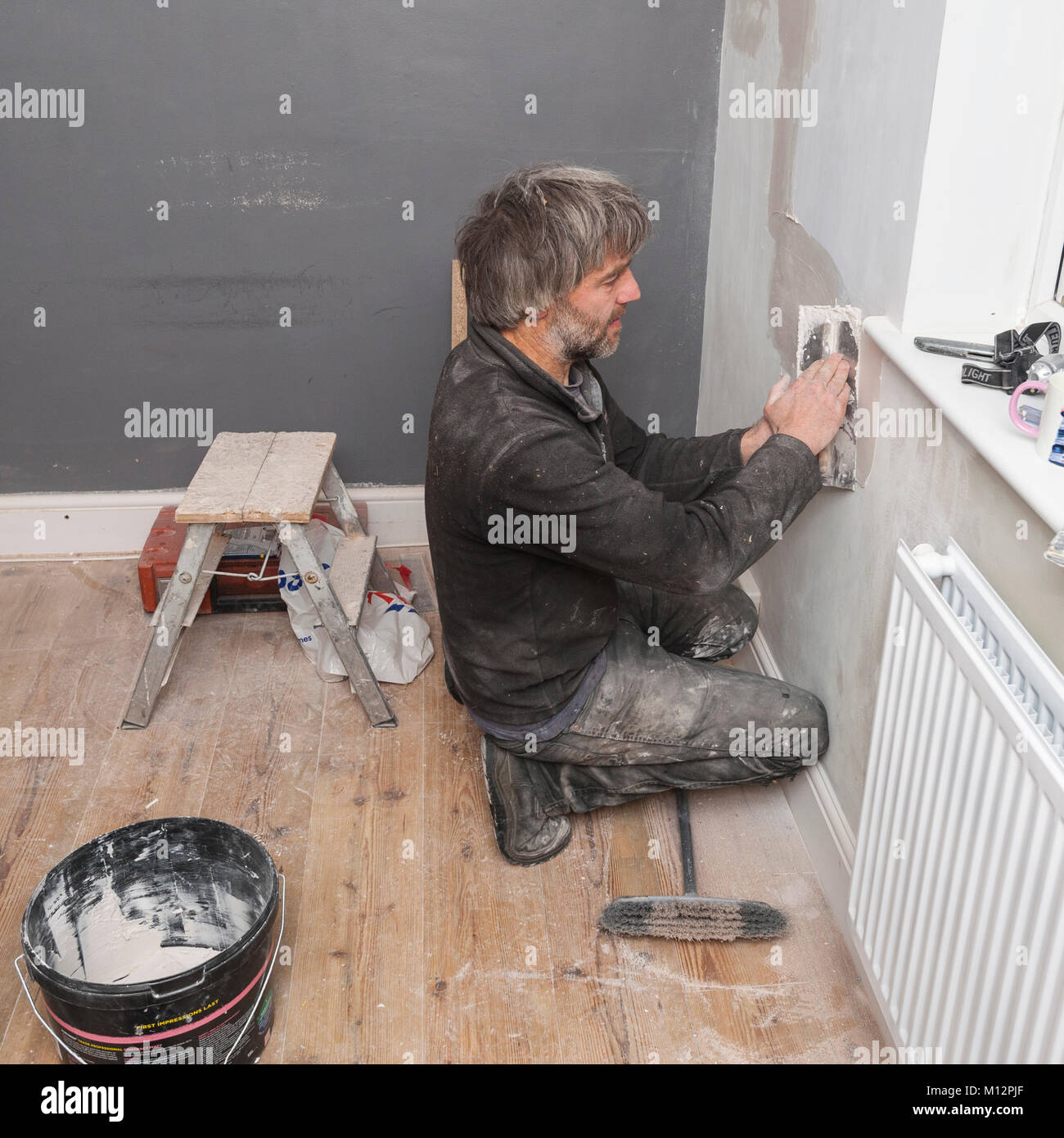 A man plastering some cracks in a wall in the Uk Stock Photo