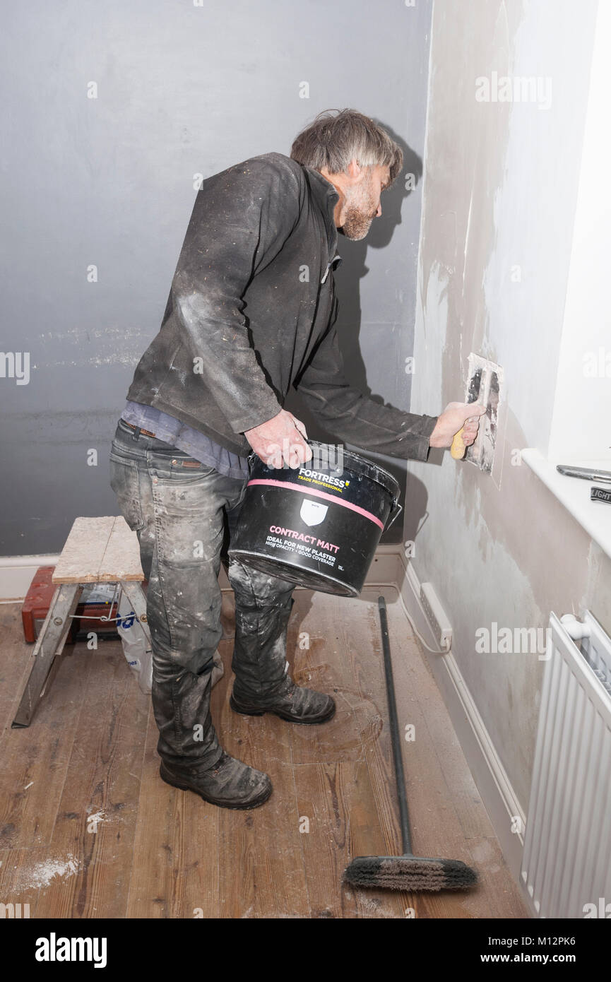 A man plastering some cracks in a wall in the Uk Stock Photo