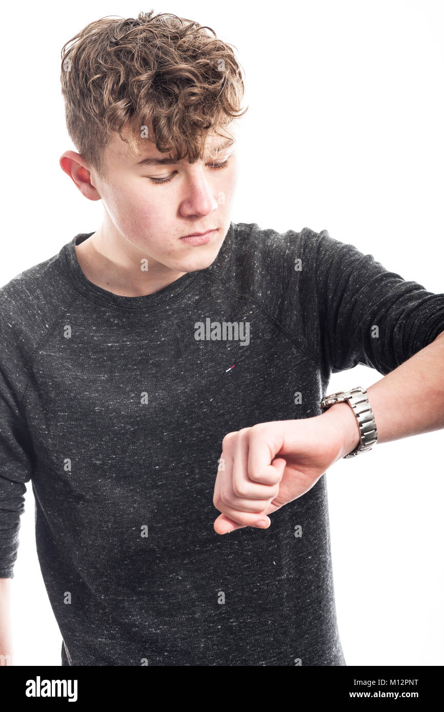 A 14 year old boy looking at his watch in the studio Stock Photo