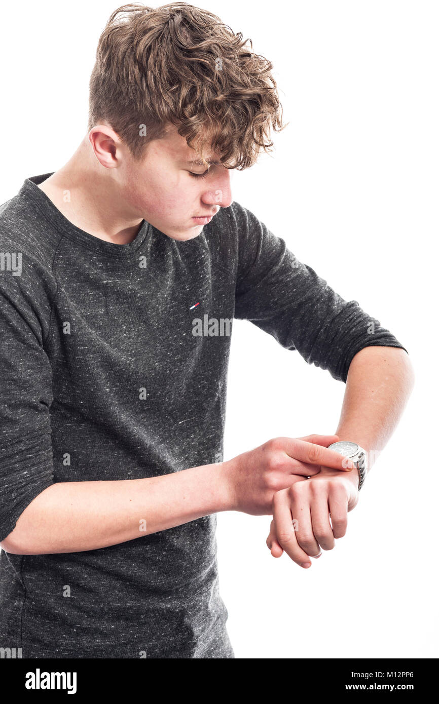 A 14 year old boy looking at his watch in the studio Stock Photo
