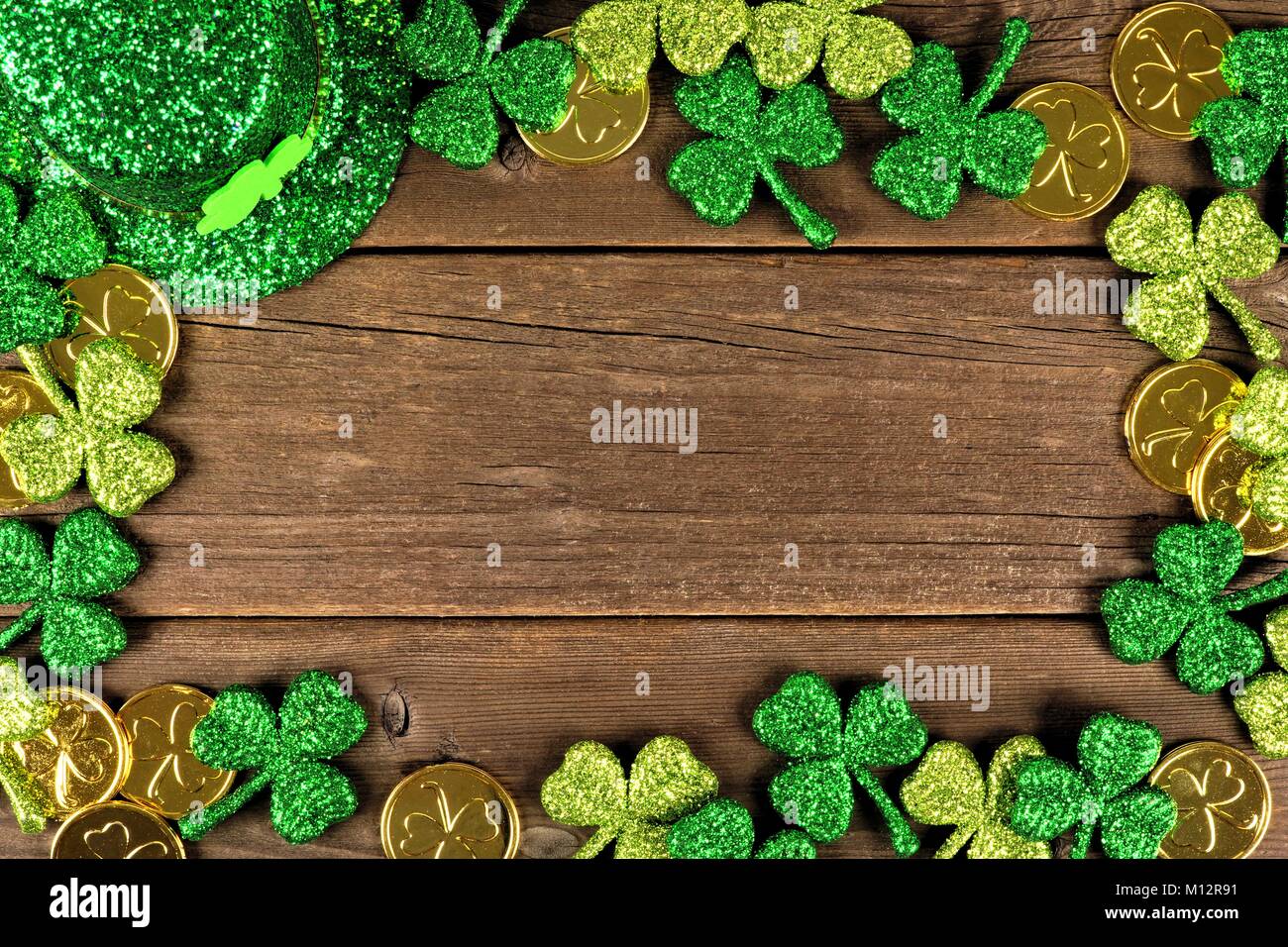 St Patricks Day frame of shamrocks, gold coins and leprechaun hat over rustic wood Stock Photo