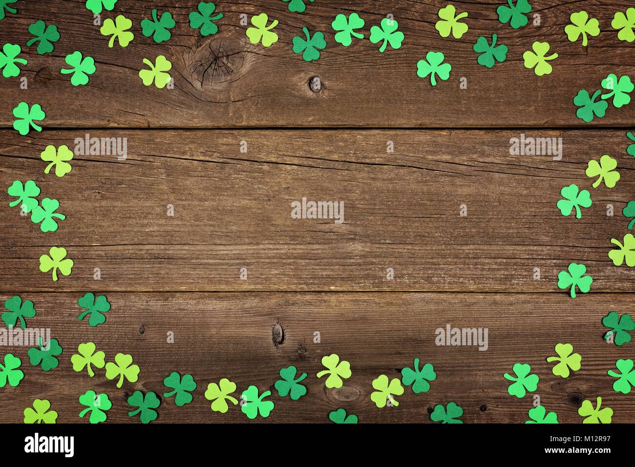St Patricks Day frame of paper shamrocks over an old rustic wood background Stock Photo