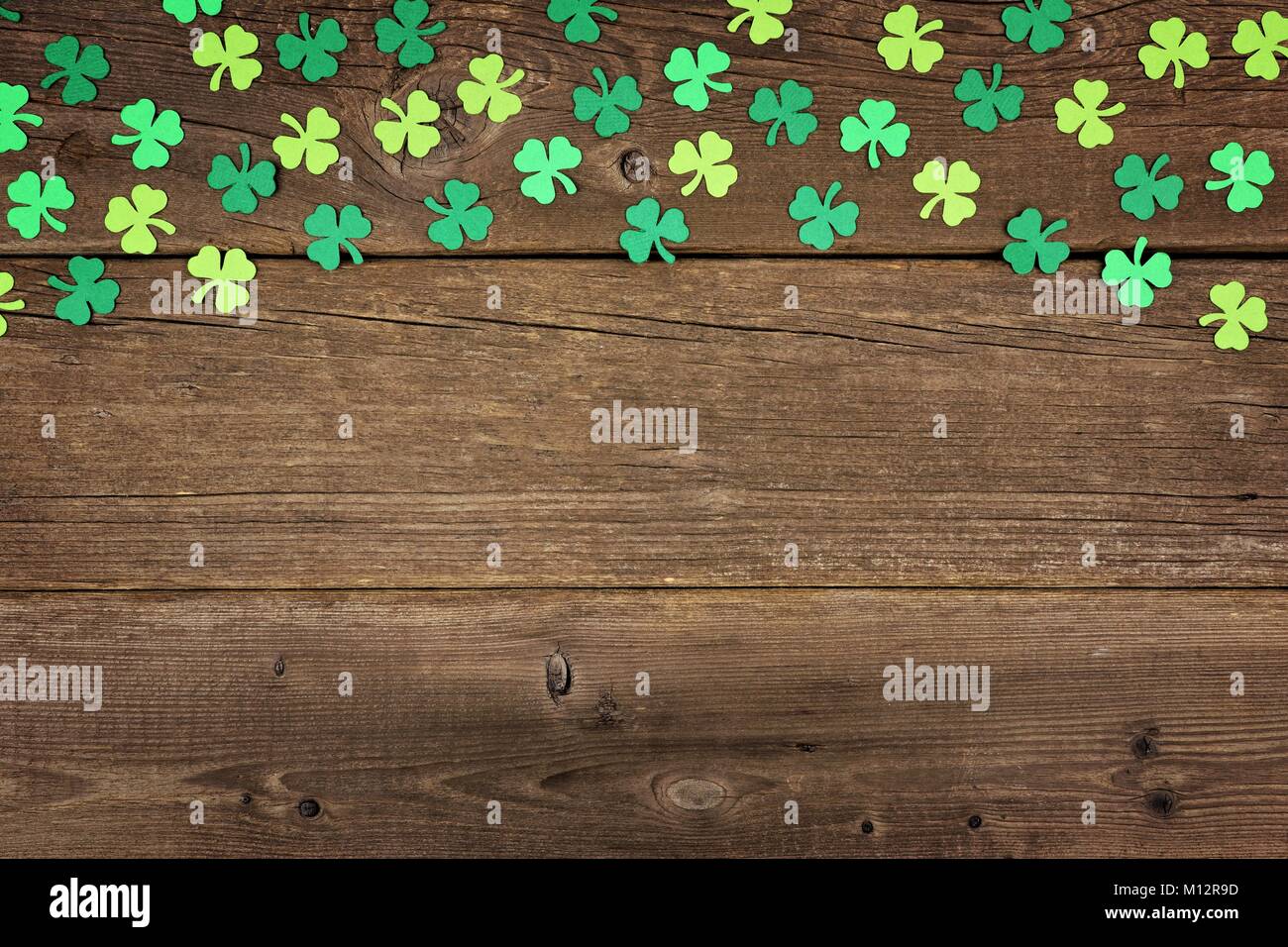 St Patricks Day top border of paper shamrocks over an old rustic wood background Stock Photo