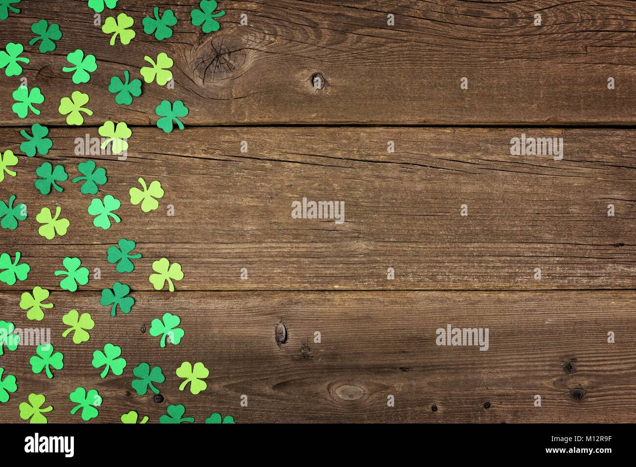 St Patricks Day side border of paper shamrocks over an old rustic wood background Stock Photo