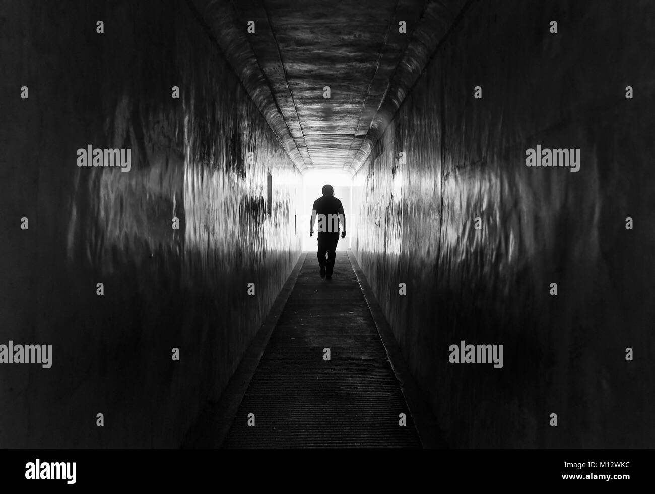 Silhouette of a man walking inside a dark tunnel inside Amber fort, India Stock Photo