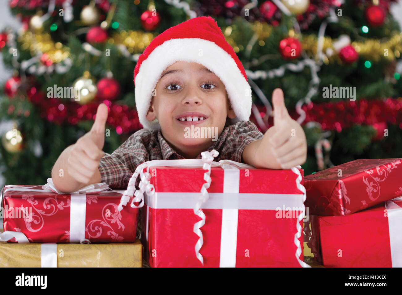 Happy little boy smiling with gift box near the Christmas tree Stock