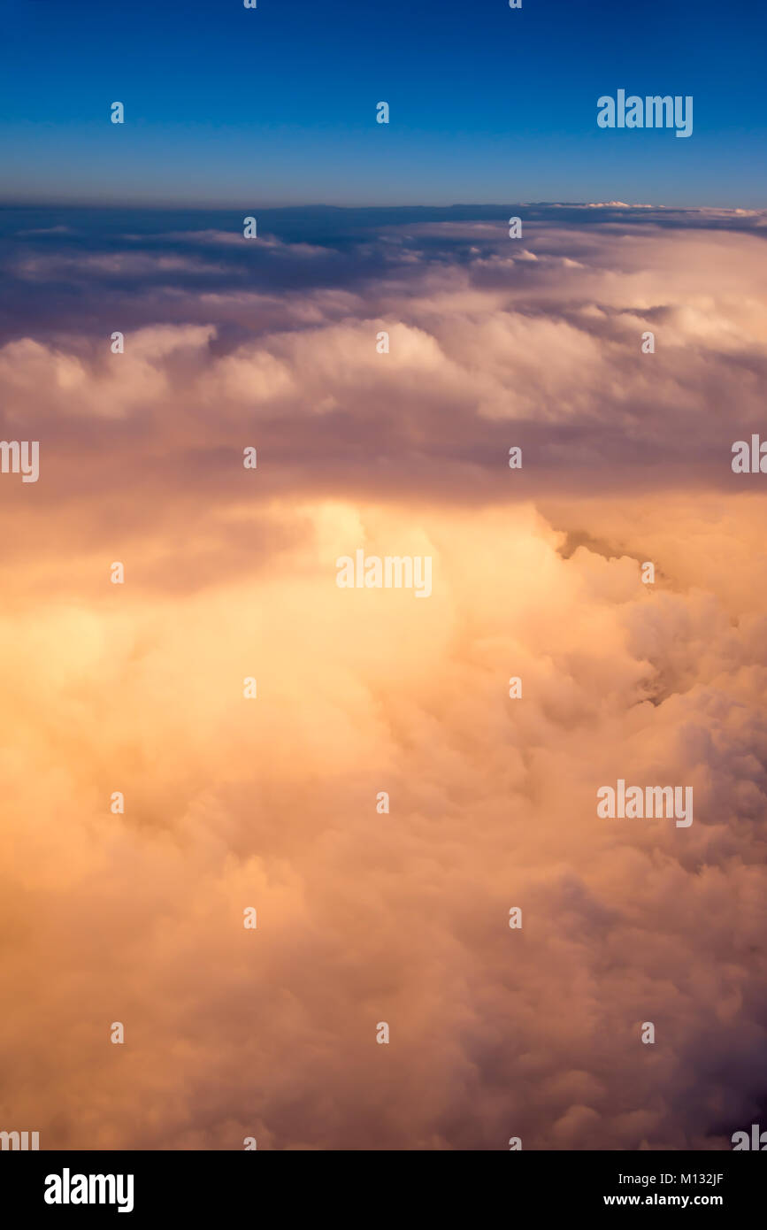 View of the sky and clouds from the airplane porthole at sunset Stock Photo